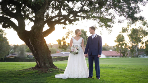 Bride and groom on golf course at Lomas Santa Fe Country Club under tree.