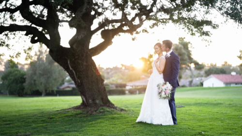 Bride and groom on golf course at Lomas Santa Fe Country Club under tree.