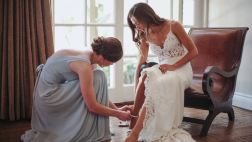 Bridesmaid helps bride put on shoes Westlake Village Inn