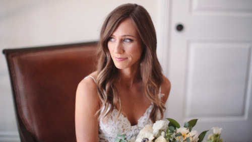 bride with bouquet looks out window smiling