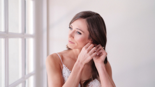 Bride putting on earring while getting ready for wedding