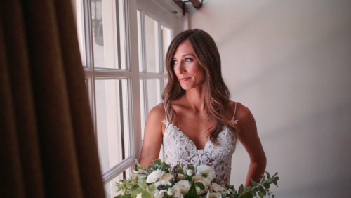 bride with bouquet stands in front of window before wedding ceremony Westlake Village Inn