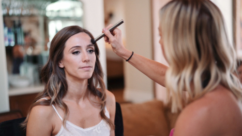 Bride getting makeup done in hotel room Westlake Village Inn