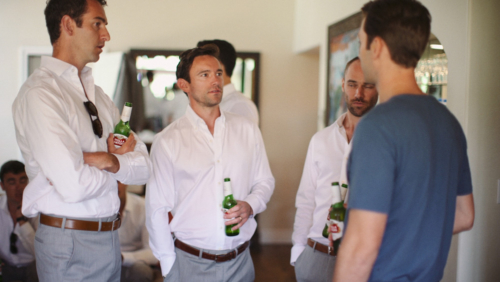 Groom hanging out with groomsmen before wedding drinking beer