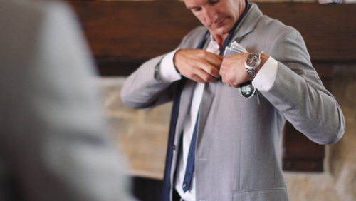 guys getting ready Groomsmen help each other put on suit before wedding