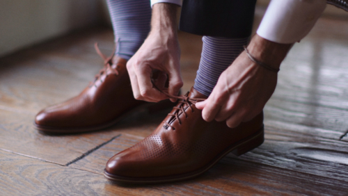 Grooms tying shoes before wedding