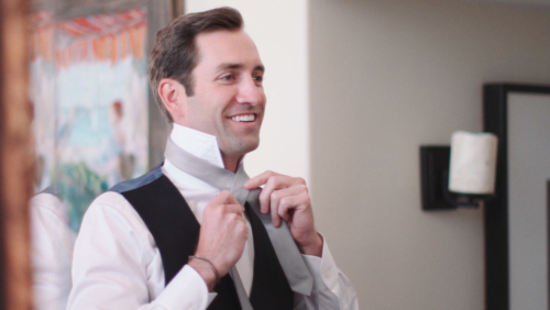 Groom tying tie before wedding