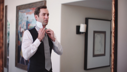 Groom tying tie before wedding