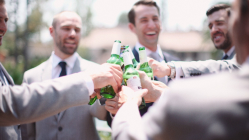 Groom hanging out with groomsmen before wedding drinking beer Stella Artrois