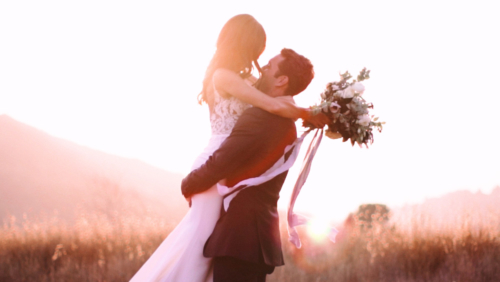 Bride can groom in field with sunlight