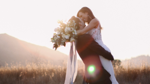 Bride and groom dancing in field