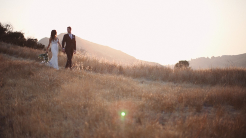 Bride and groom waling in field at sunset Brookview Ranch Malibu