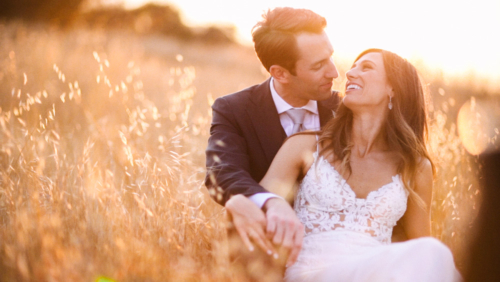 Bride and groom smiling and sitting in a field at sunset Brookview Ranch Malibu