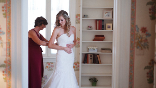 Mom helps bride lace up wedding dress