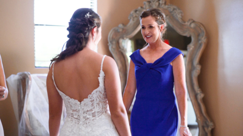 Mom helps bride in wedding dress before ceremony