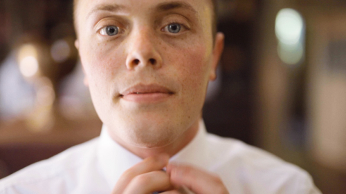 Groom adjusting tie before wedding