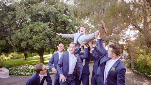 Groomsmen hold up groom