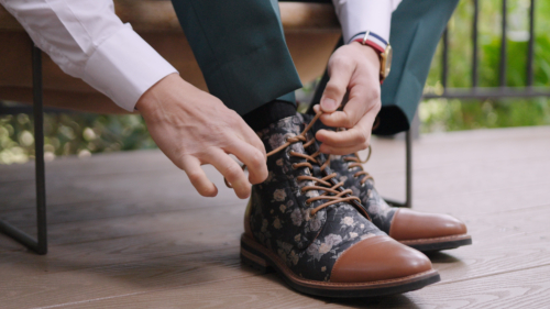 Groom puting on boots at wedding